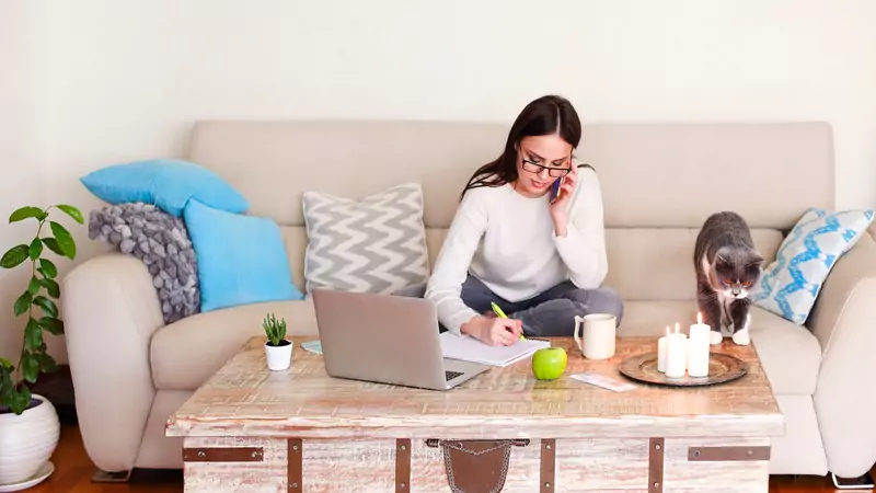 remote-nurse-working-from-home-on-laptop-while-taking-call-and-documenting-notes