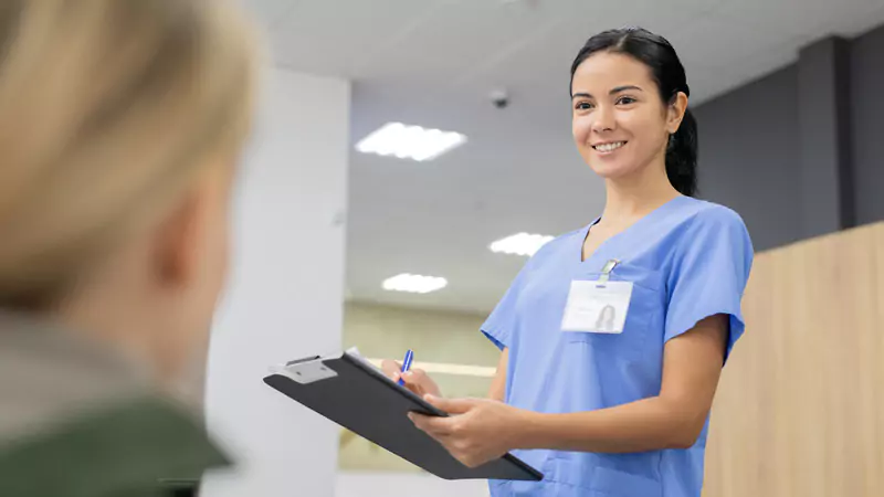 smiling-on-site-nurse-in-scrubs-taking-notes-and-providing-in-person-patient-care